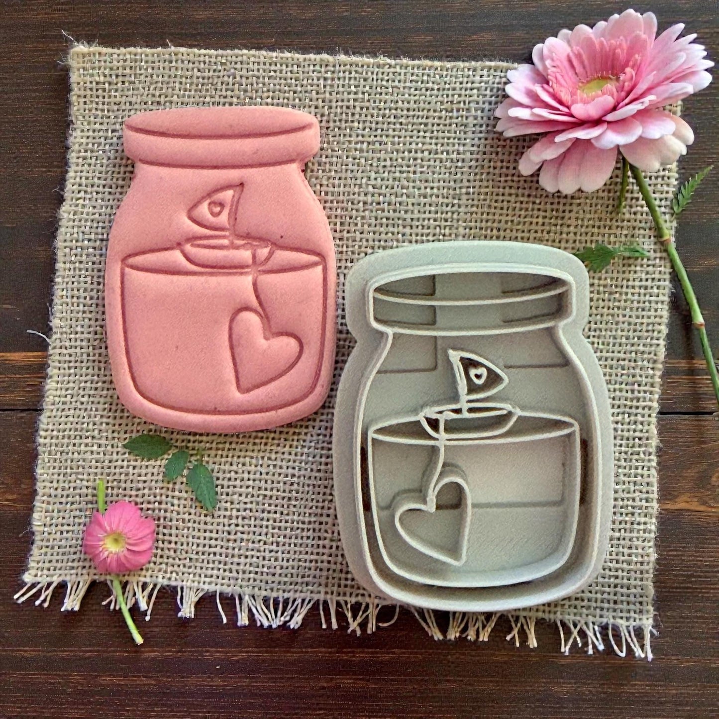 Candle jar clay piece next to matching cutter on burlap