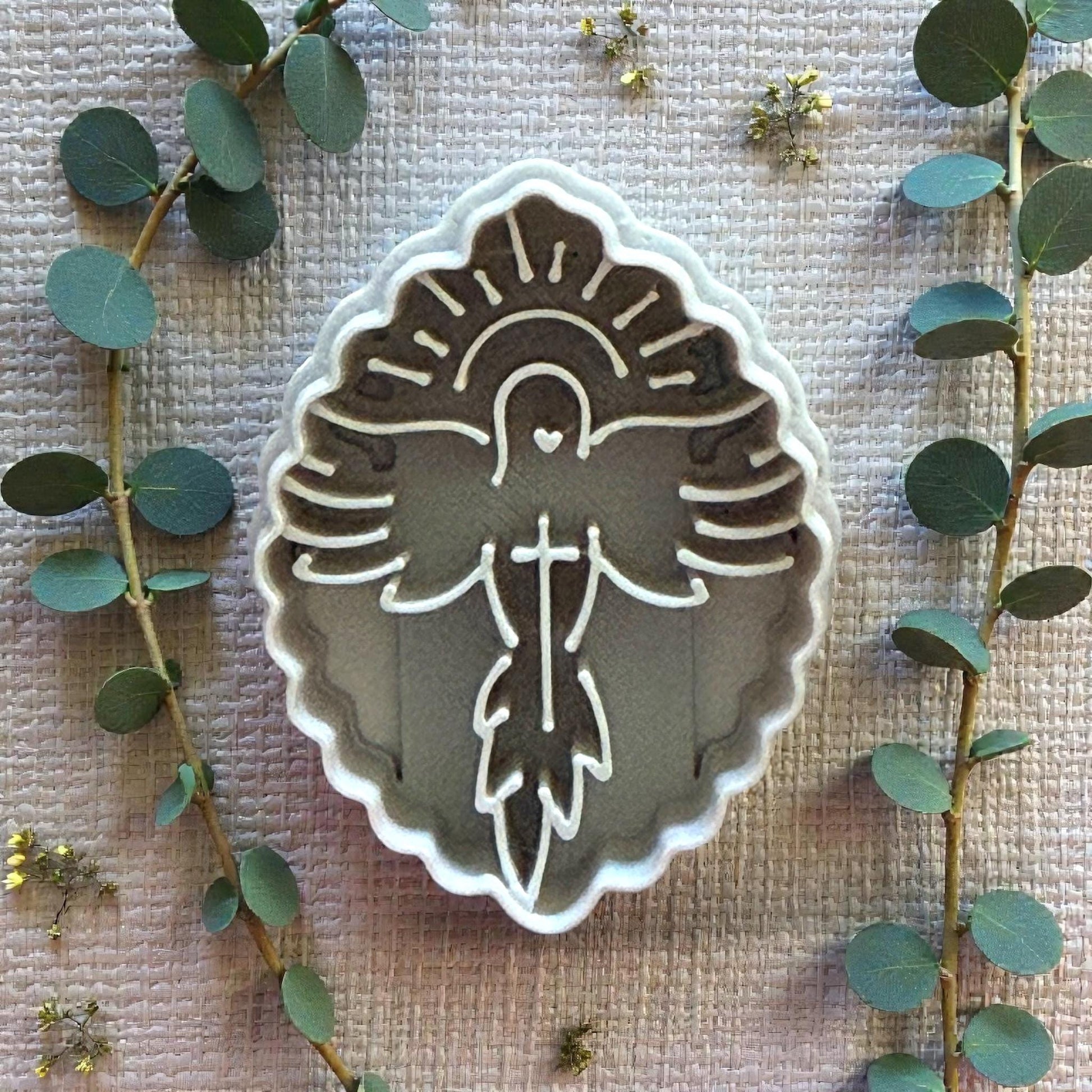 Dove imprint on white tile surrounded by greenery and flowers
