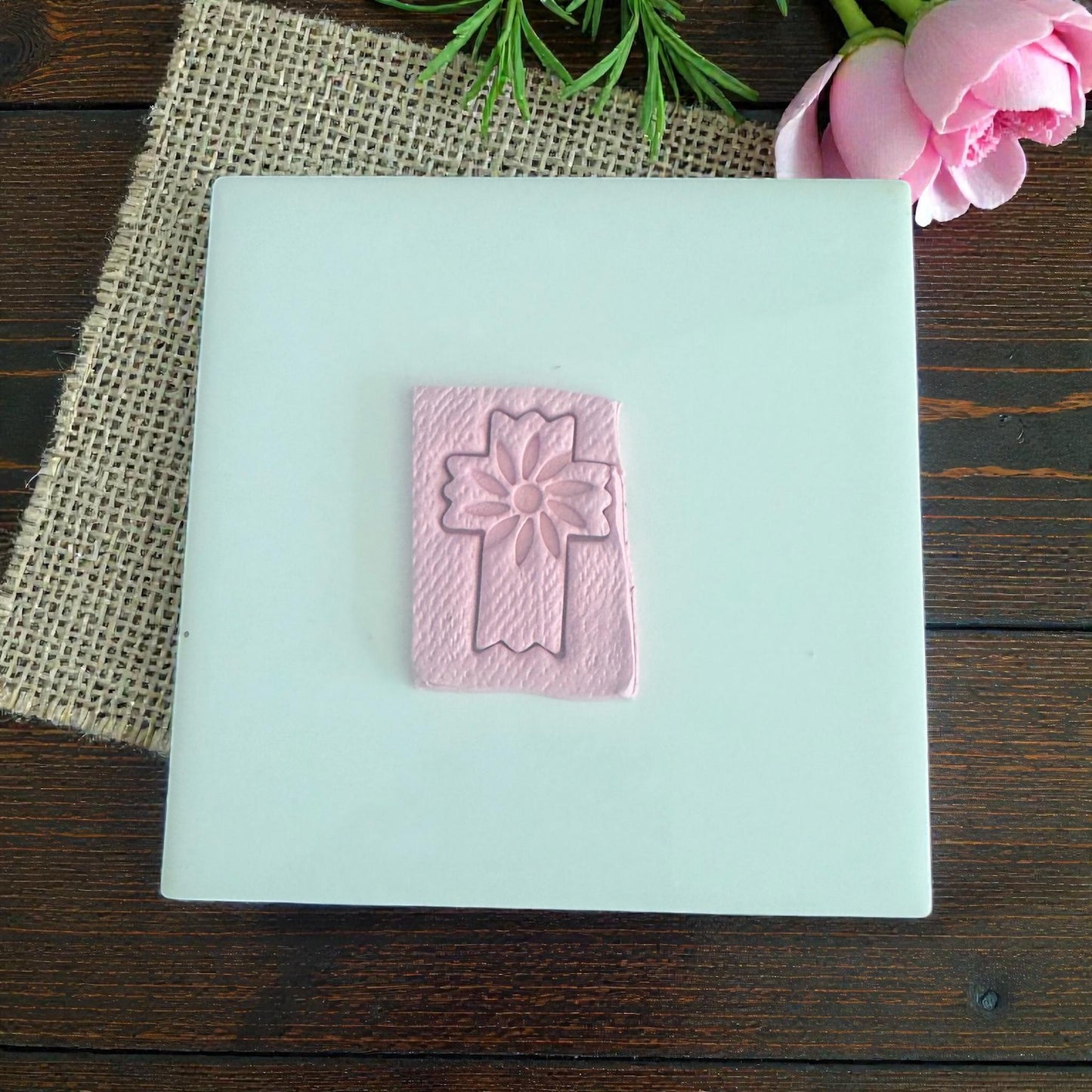 pink clay impression of floral cross on white tile