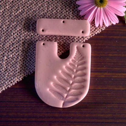 Close-up of pink clay fern U-shape with bar topper