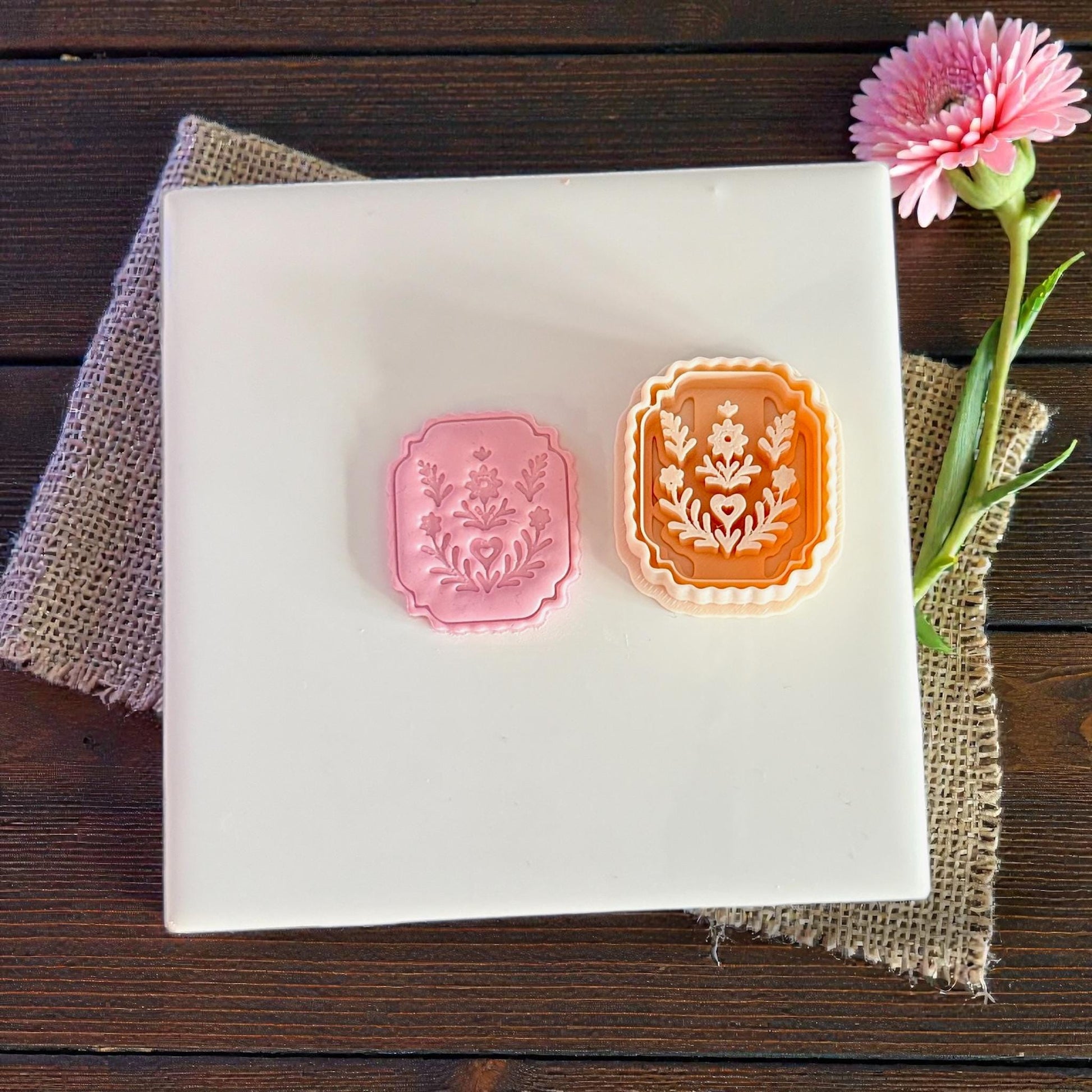 two floral plaque pieces and cutter shown on white tile with flower