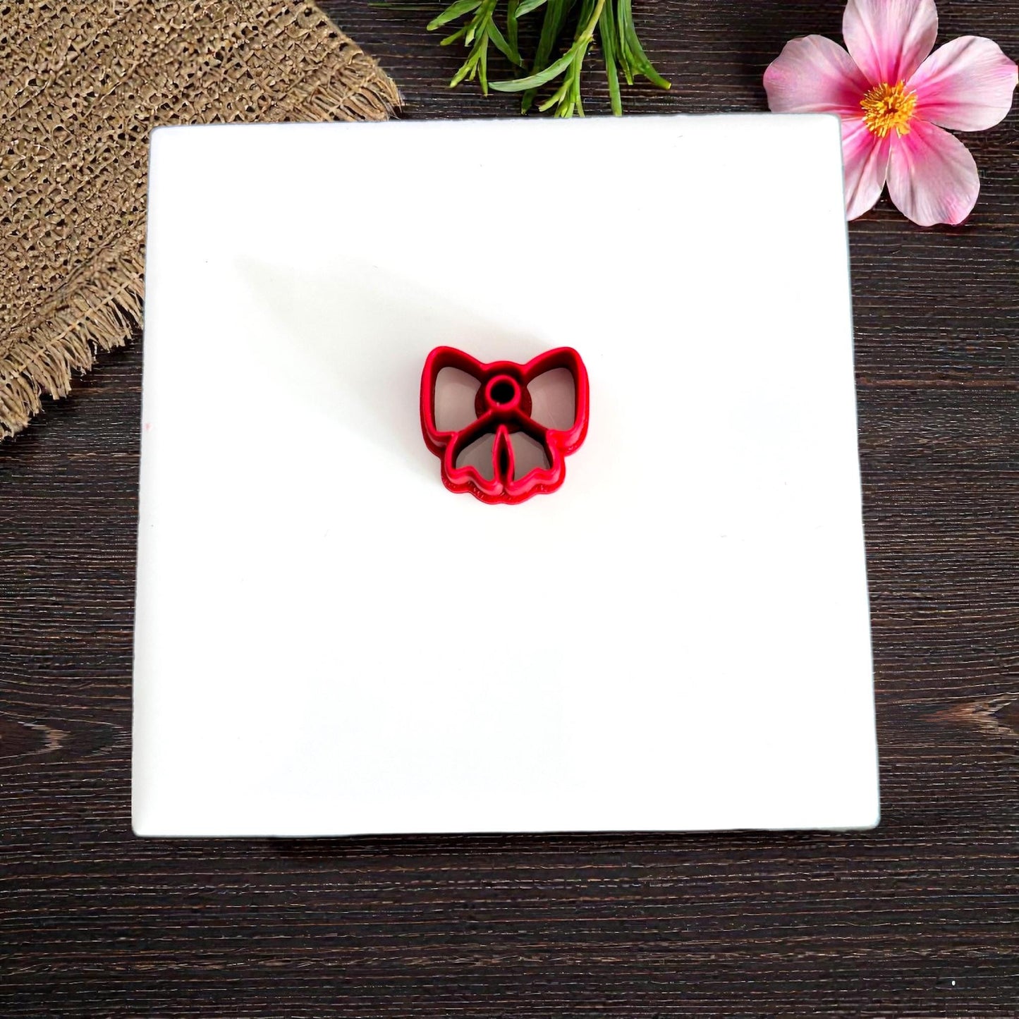 Red bow cookie-style cutter on white tile with flowers
