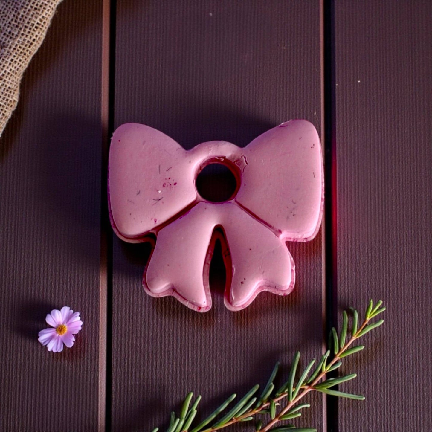 Close-up of large pink bow clay piece on dark wood background