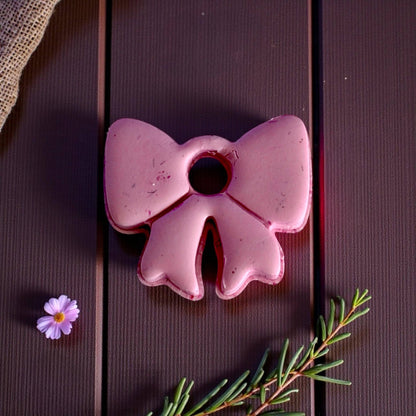 Close-up of large pink bow clay piece on dark wood background