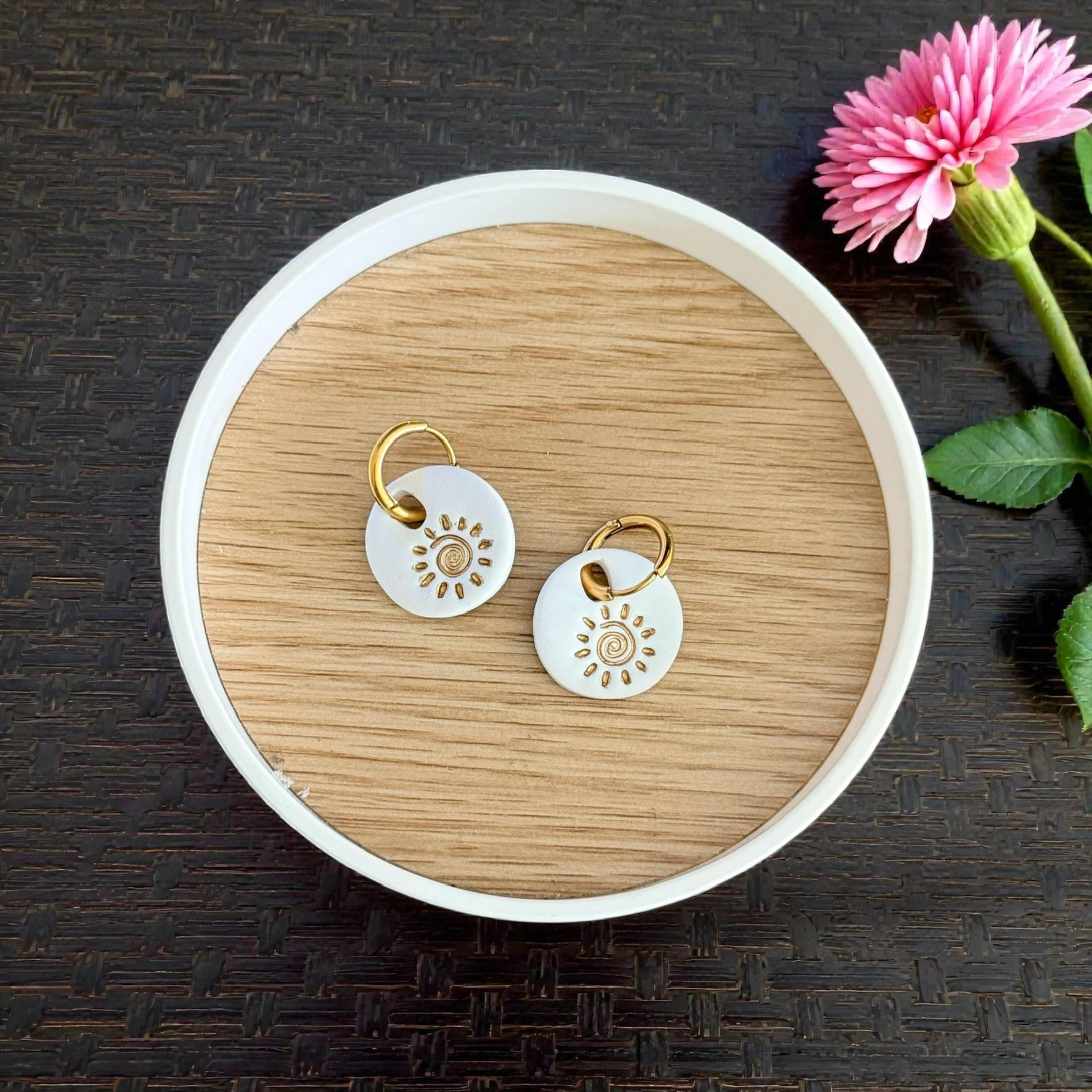 Pair of white sun swirl charms on wooden dish