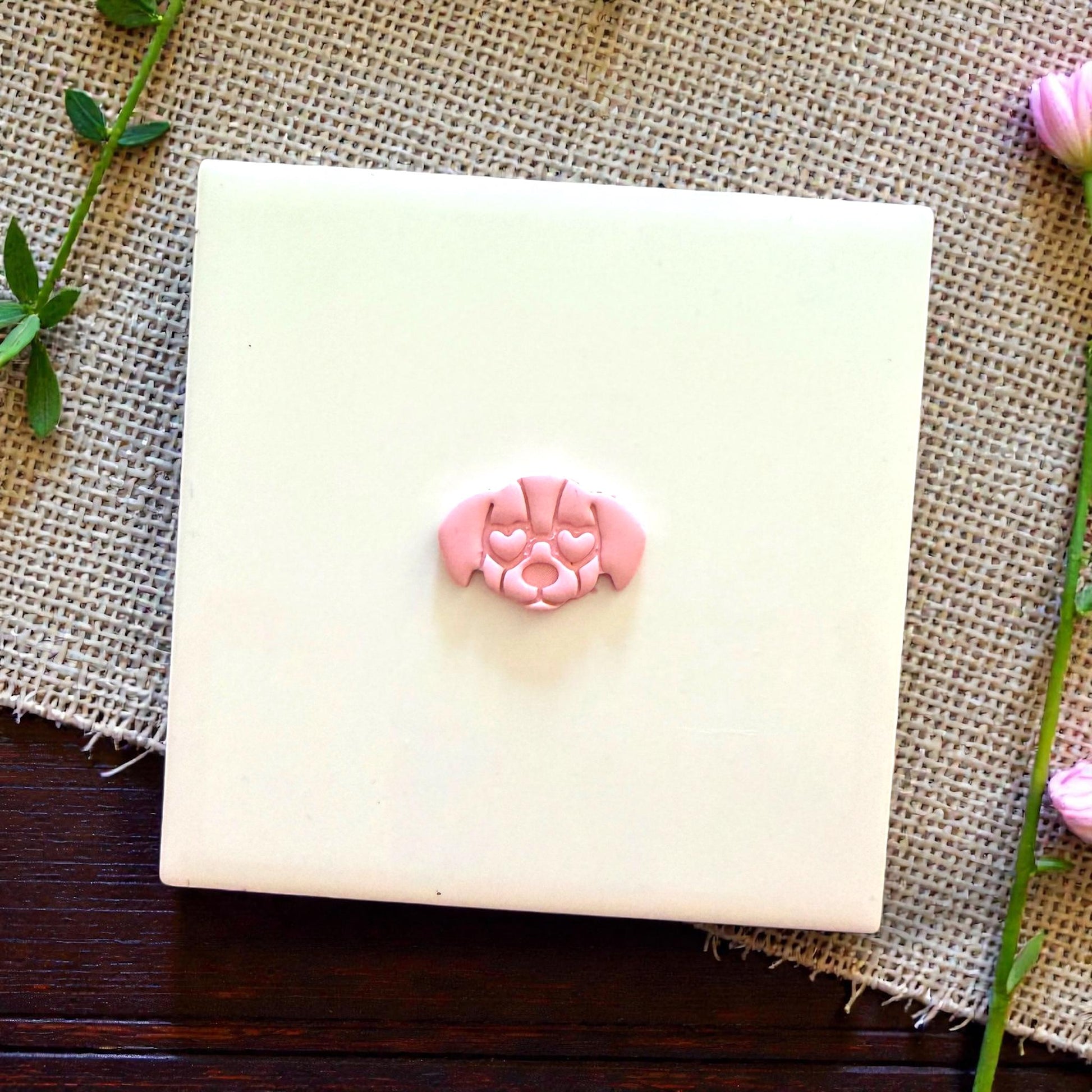 small puppy face clay piece on white tile