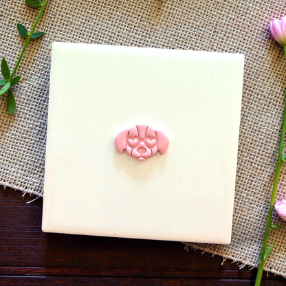 small puppy face clay piece on white tile