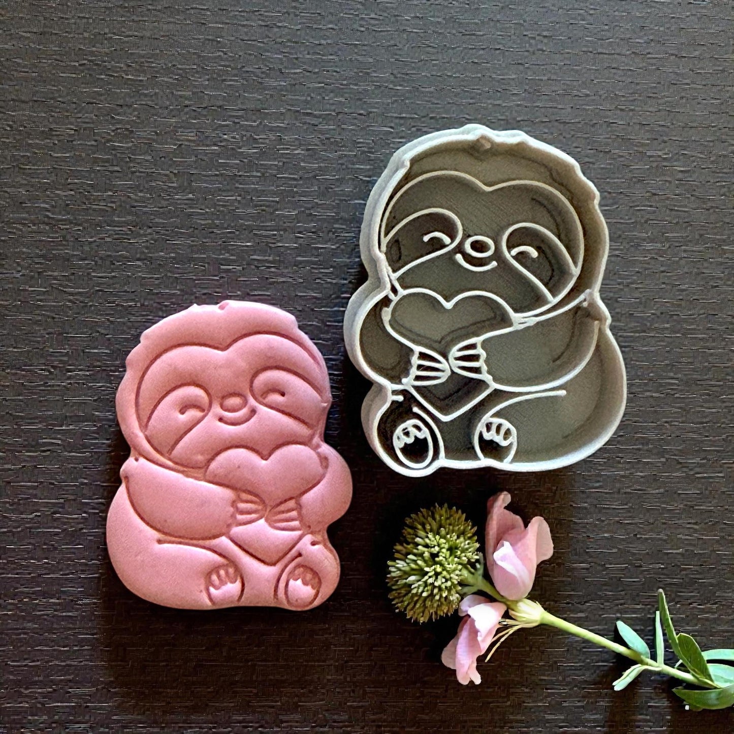 sloth cutter beside sloth clay piece on dark background