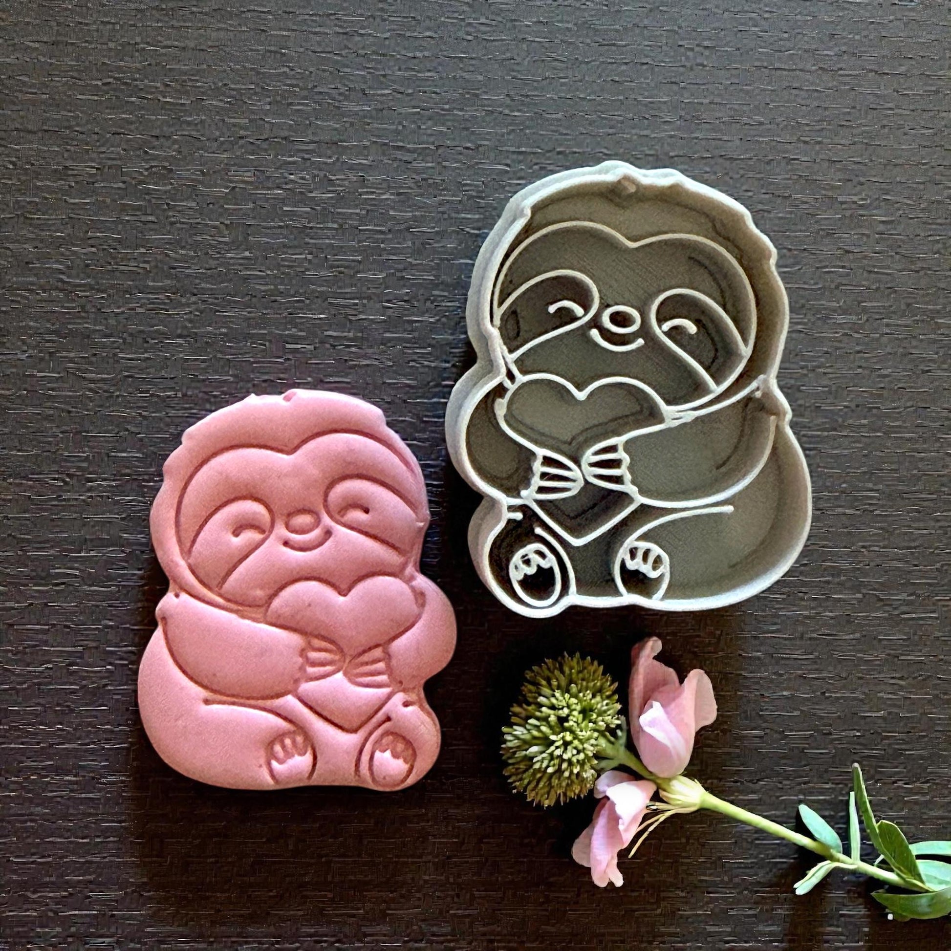 sloth cutter beside sloth clay piece on dark background