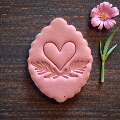 close up pink clay heart with leaf details