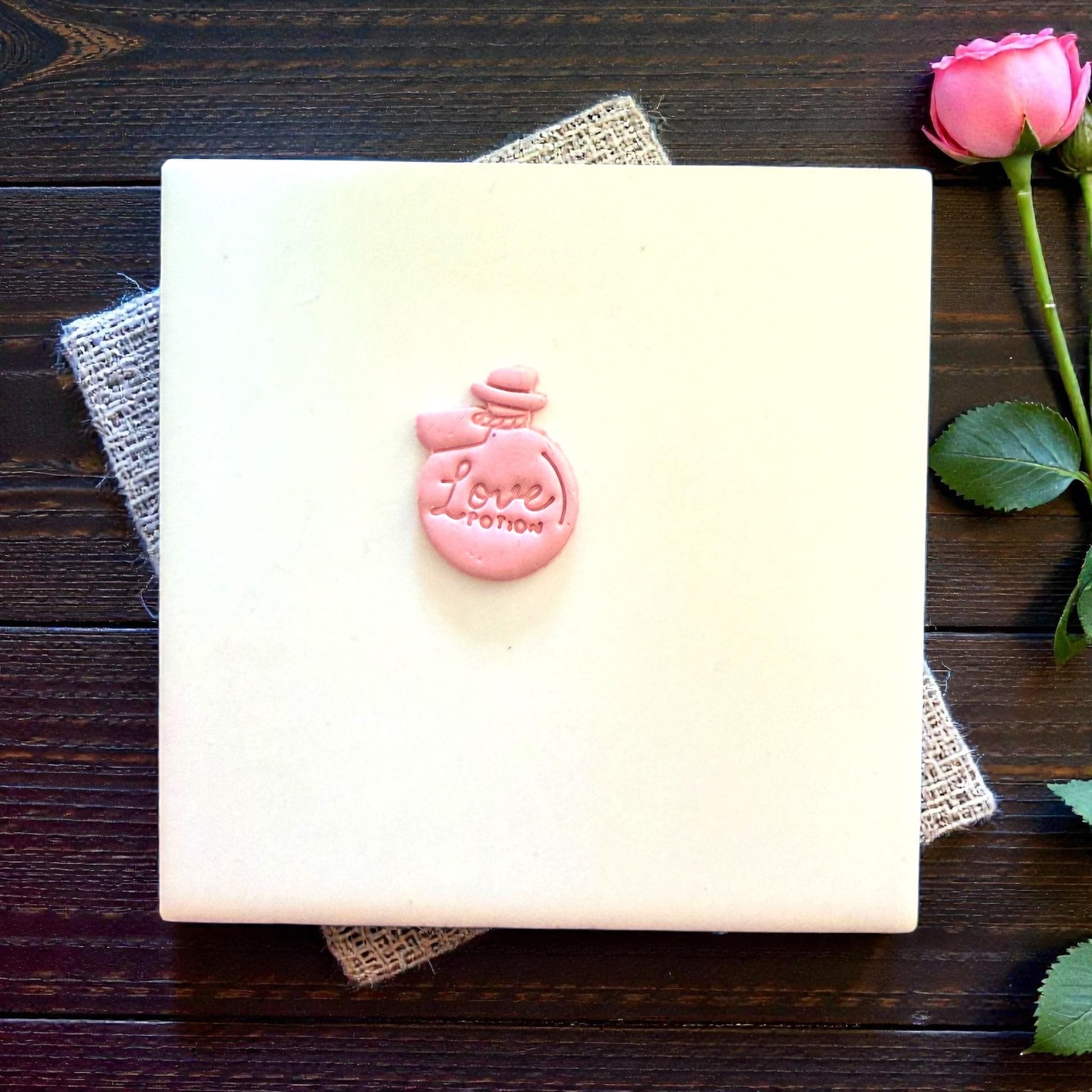 small pink love potion clay shape centered on tile