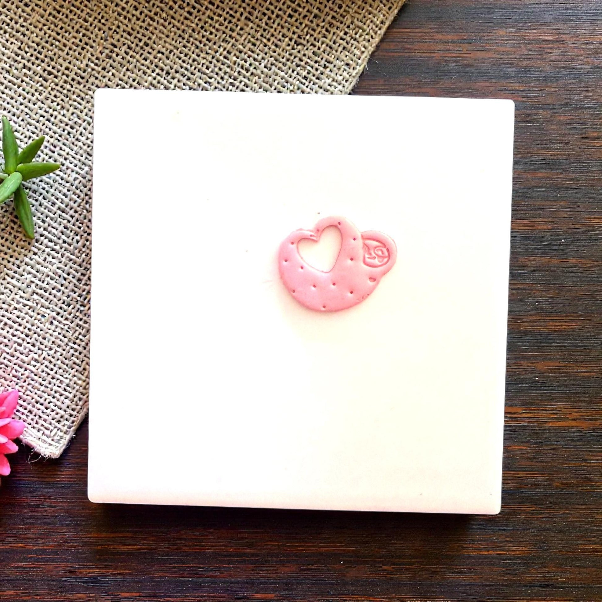Small pink sloth heart clay piece centered on tile