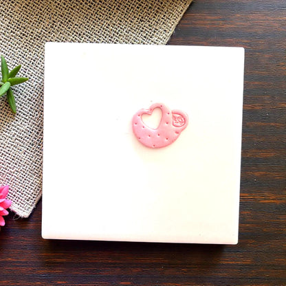 Small pink sloth heart clay piece centered on tile