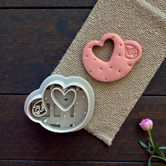 Cutter and finished sloth heart clay piece on burlap