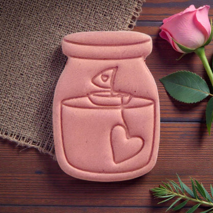 Close-up clay piece shaped like candle jar with heart tag