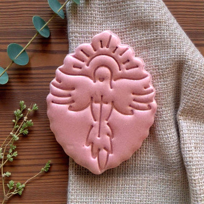 Clay imprint of dove with cross beside matching cutter