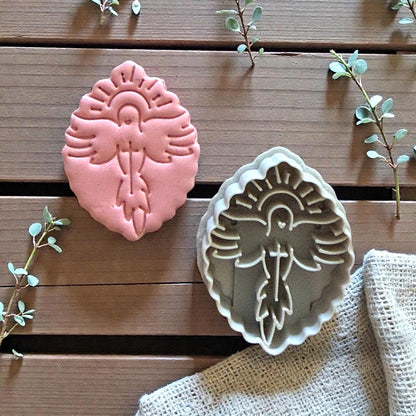 Pink clay imprint of dove with halo and cross