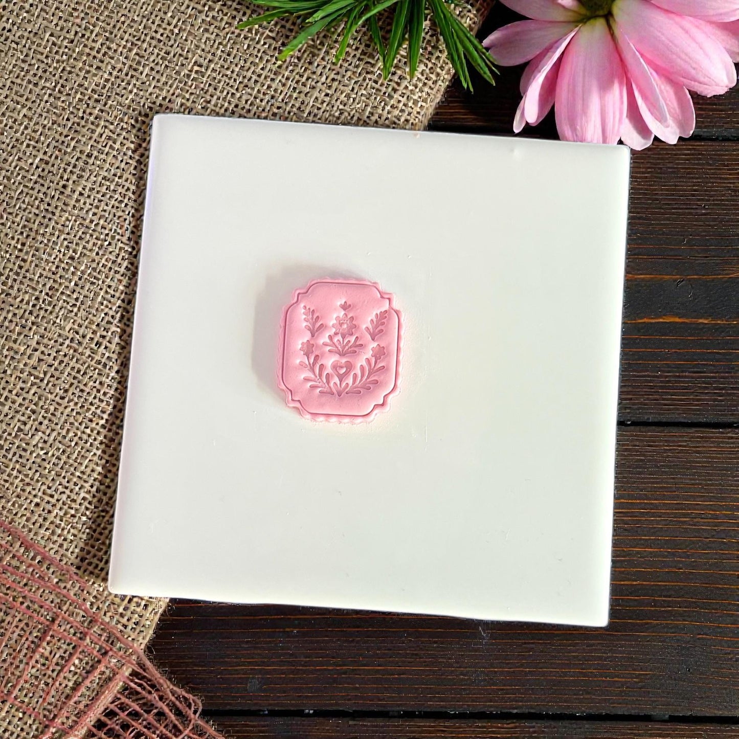 finished pink clay folk floral plaque on white tile with greenery