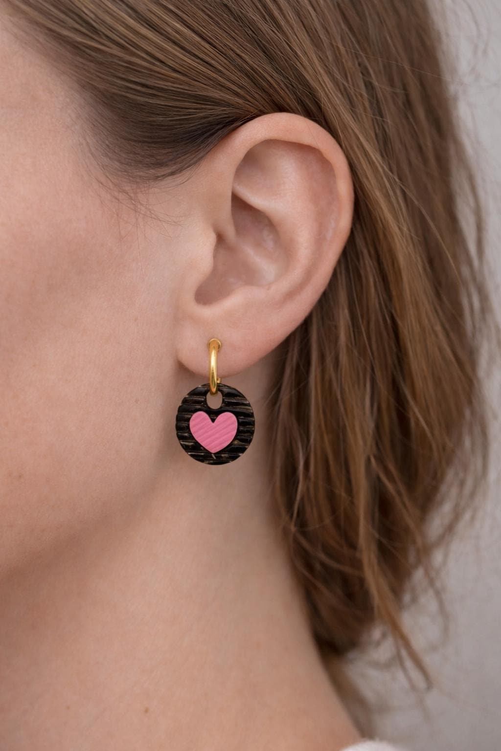 girls wearing black striped round and pink heart huggies earrings