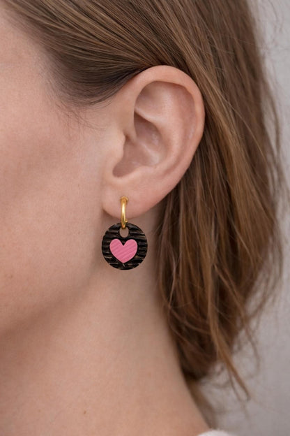 girls wearing black striped round and pink heart huggies earrings