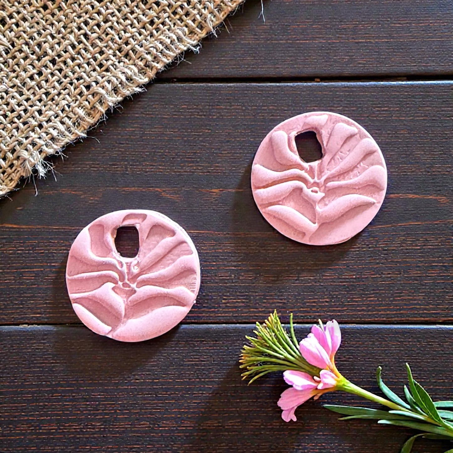 pink matisse flower clay charms displayed on wood