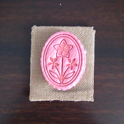small floral cameo clay cutout displayed on burlap