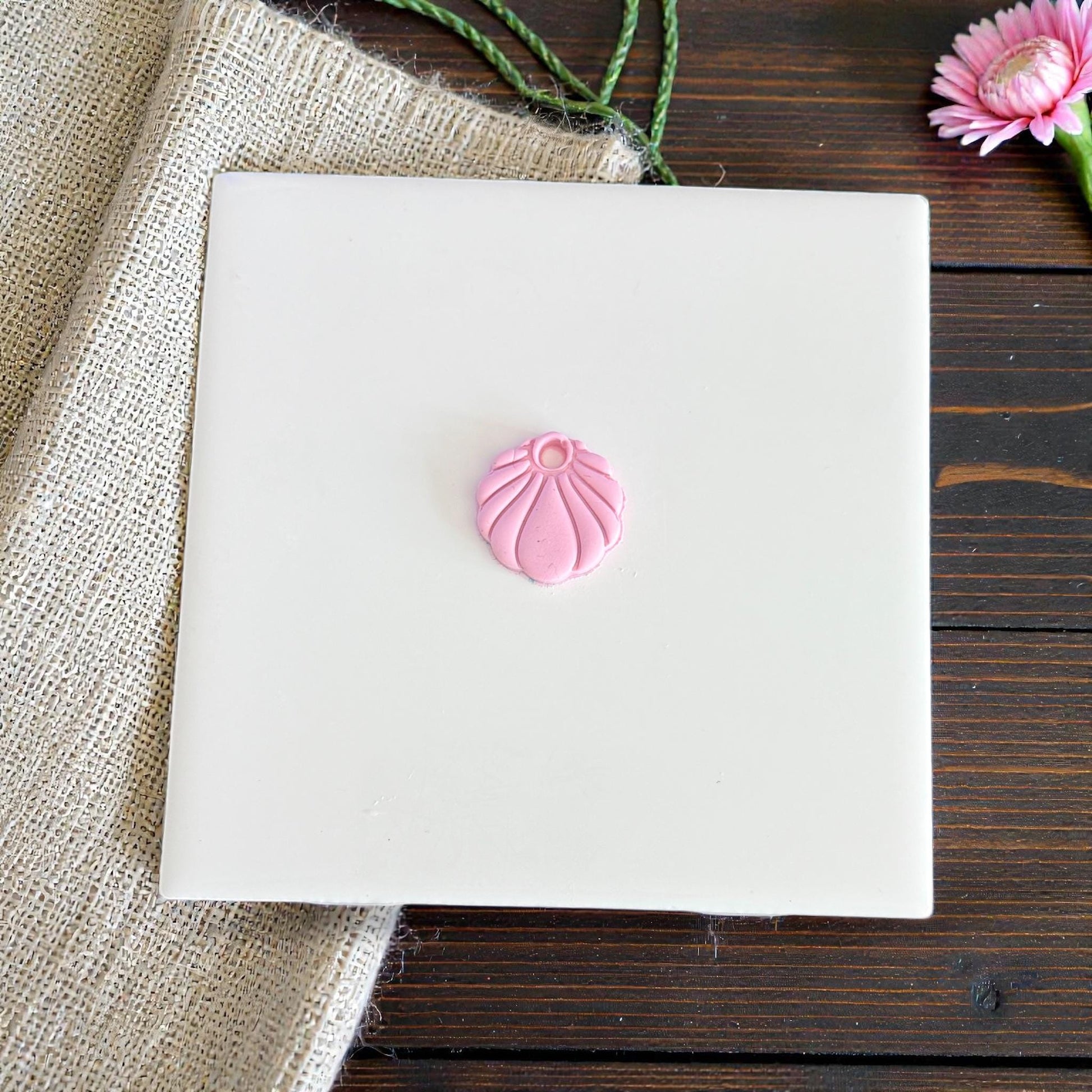 tiny pink seashell charm shown centered on tile