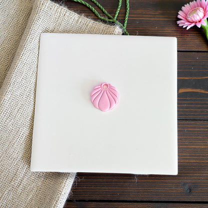 tiny pink seashell charm shown centered on tile