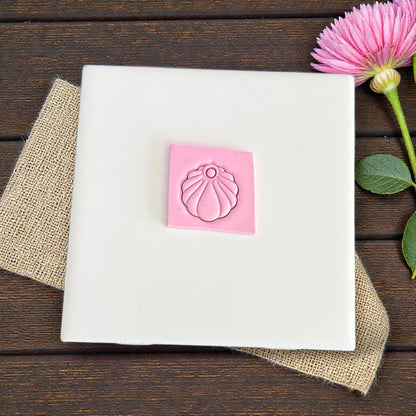 small scallop shell charm impression in pink clay