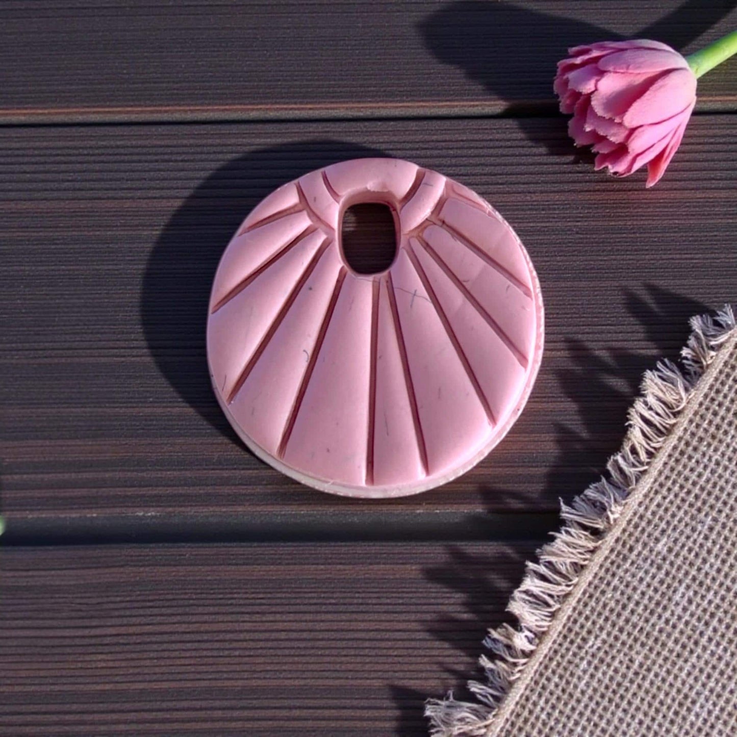 Close-up pink sunburst charm with radiating lines