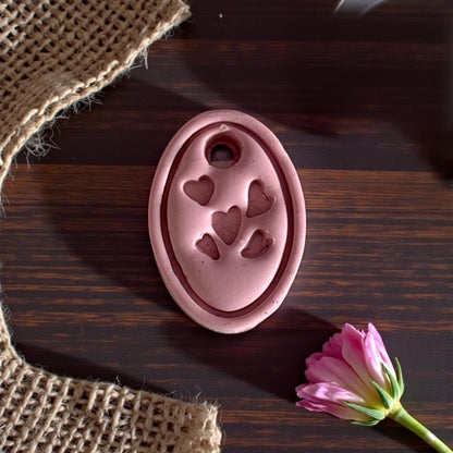 close up of pink oval heart charm impression