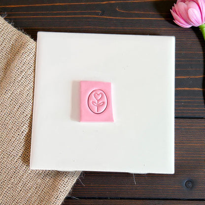 heart flower oval charm cutter pressed in pink clay on tile