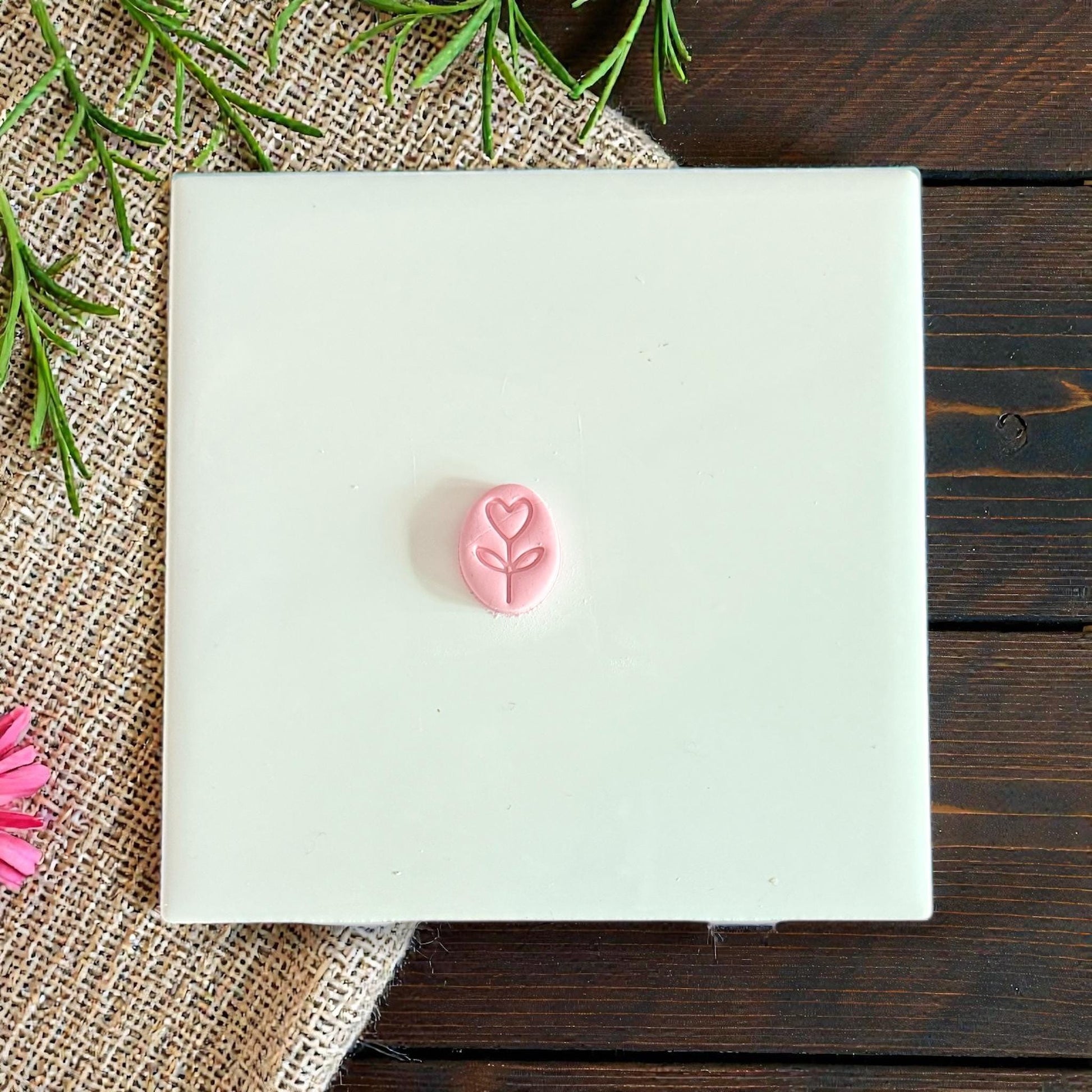 small oval heart stem clay charm on white tile