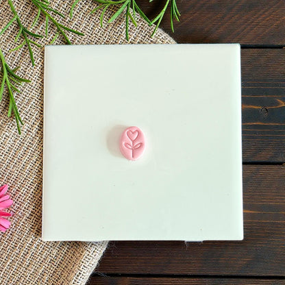 small oval heart stem clay charm on white tile