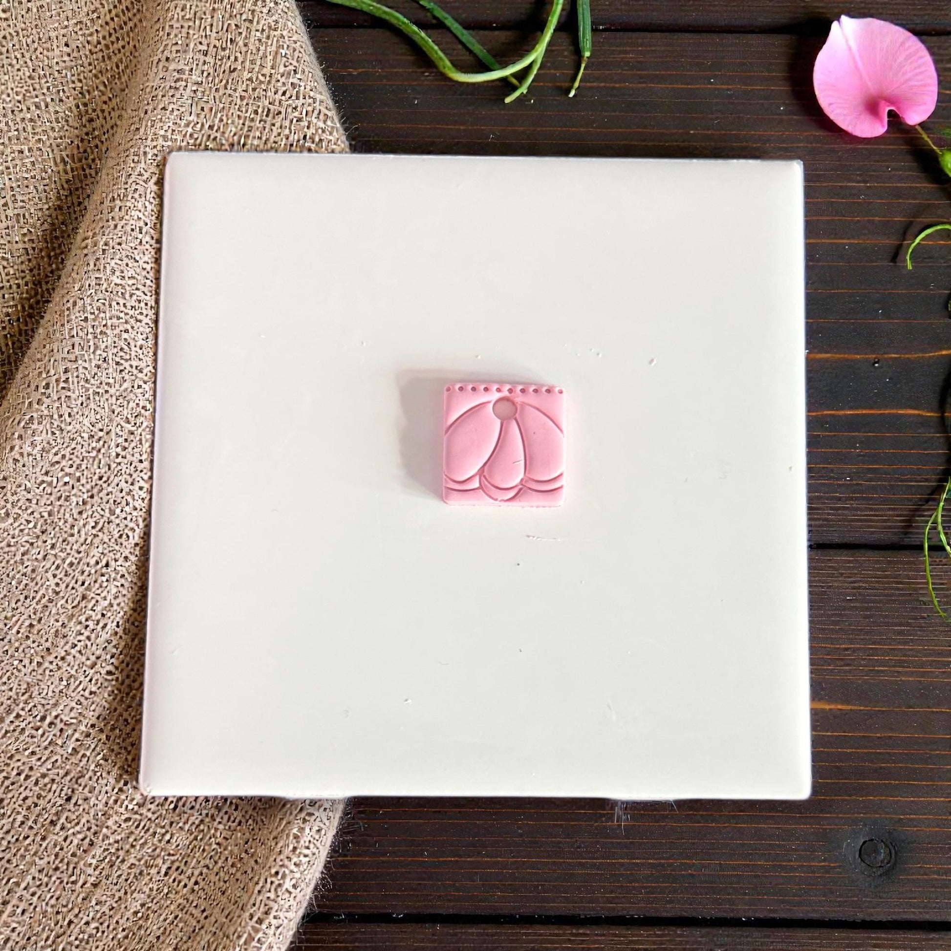 small pink clay charm with petal arch pattern