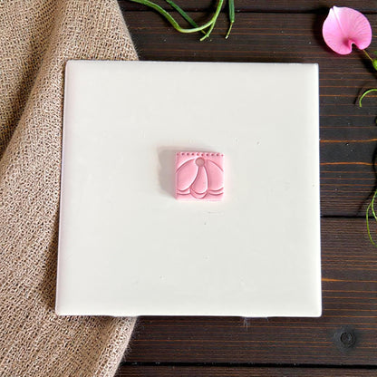 small pink clay charm with petal arch pattern