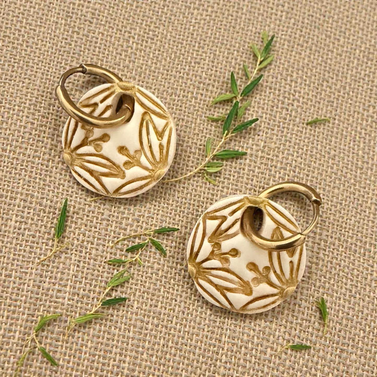 gold botanical circle earrings displayed on wood