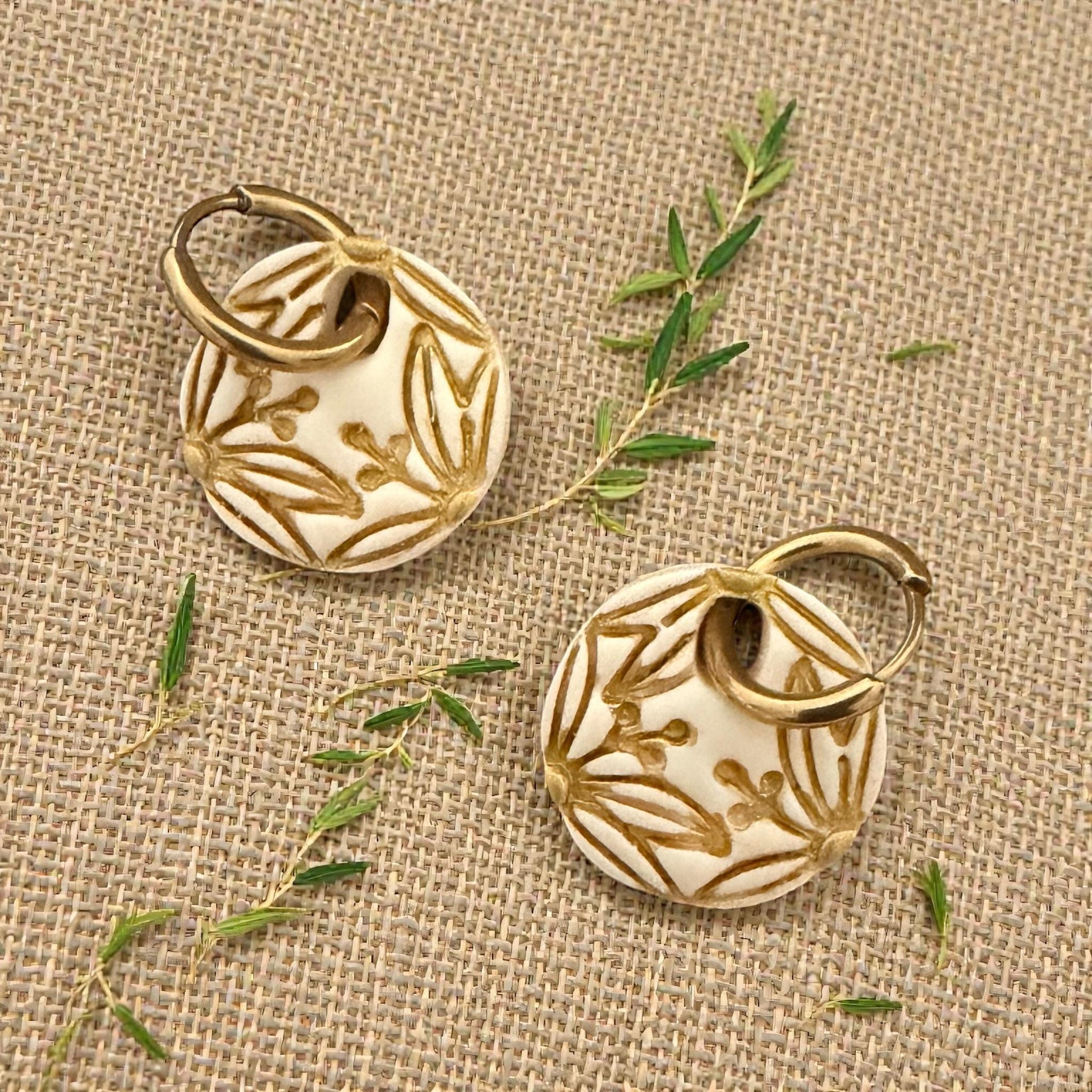 gold botanical circle earrings displayed on wood