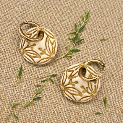 gold botanical circle earrings displayed on wood