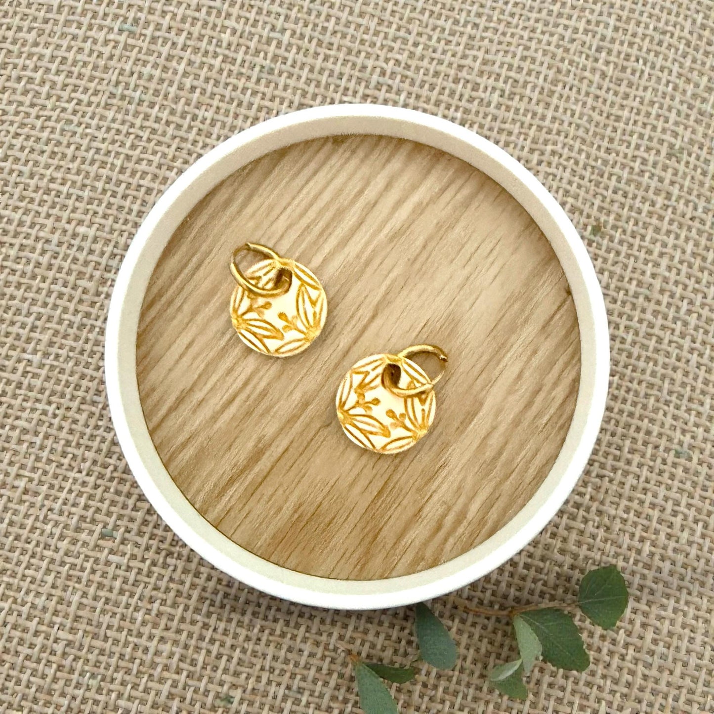 gold botanical circle earrings displayed on wood