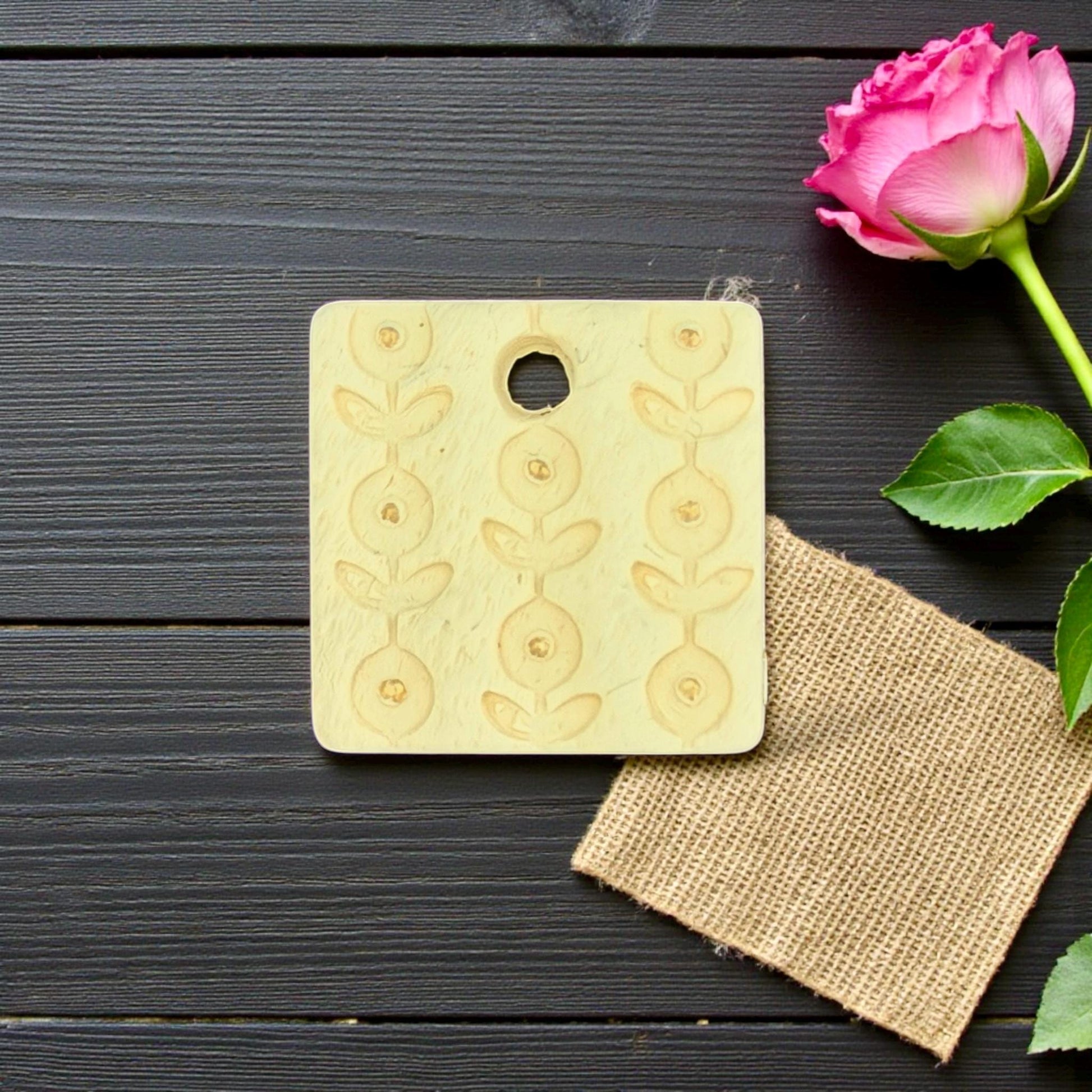 yellow clay charm with floral pattern on wood
