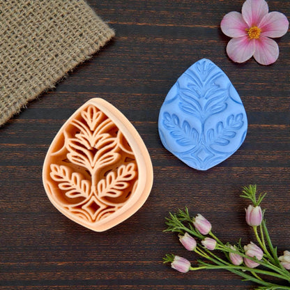 Close-up of boho teardrop leaf cutter next to detailed clay impression
