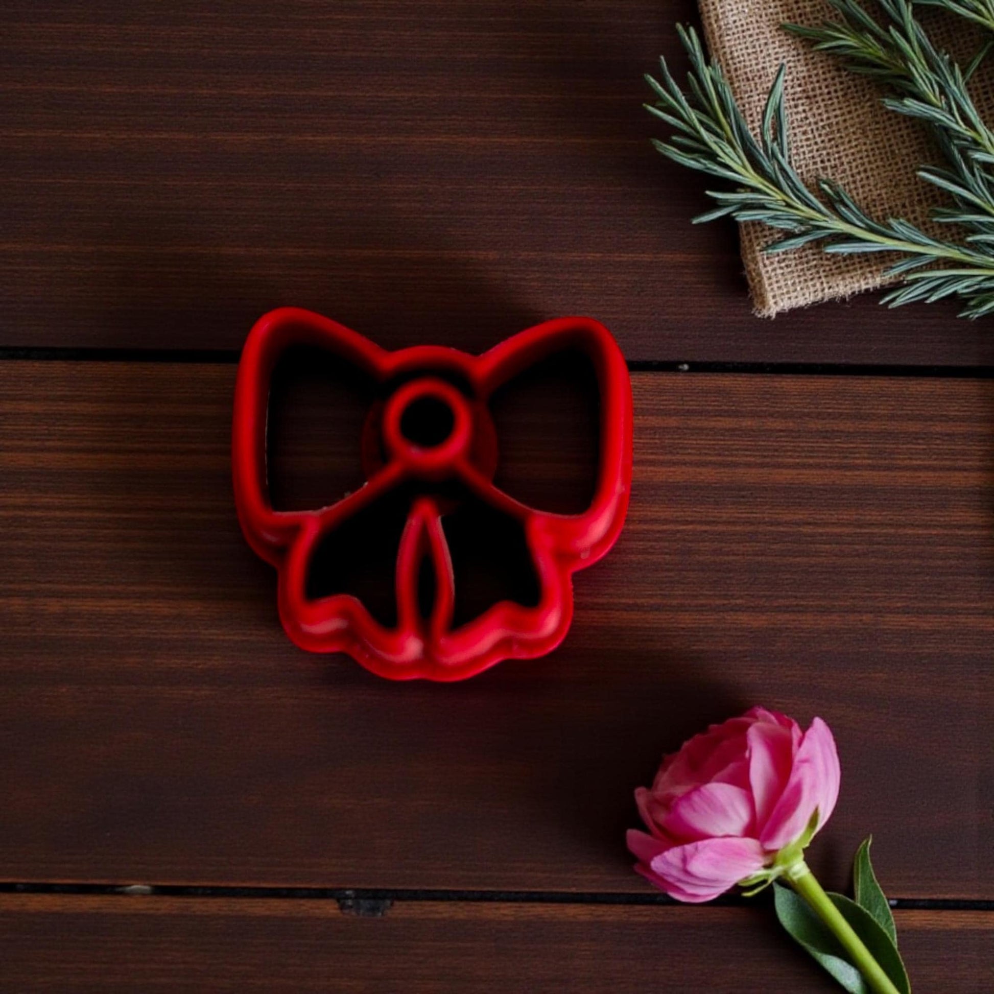 Red bow cutter close-up on dark wood with greenery