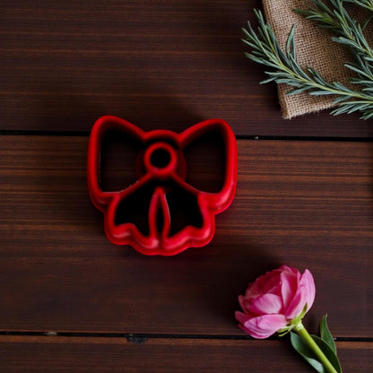 Red bow cutter close-up on dark wood with greenery