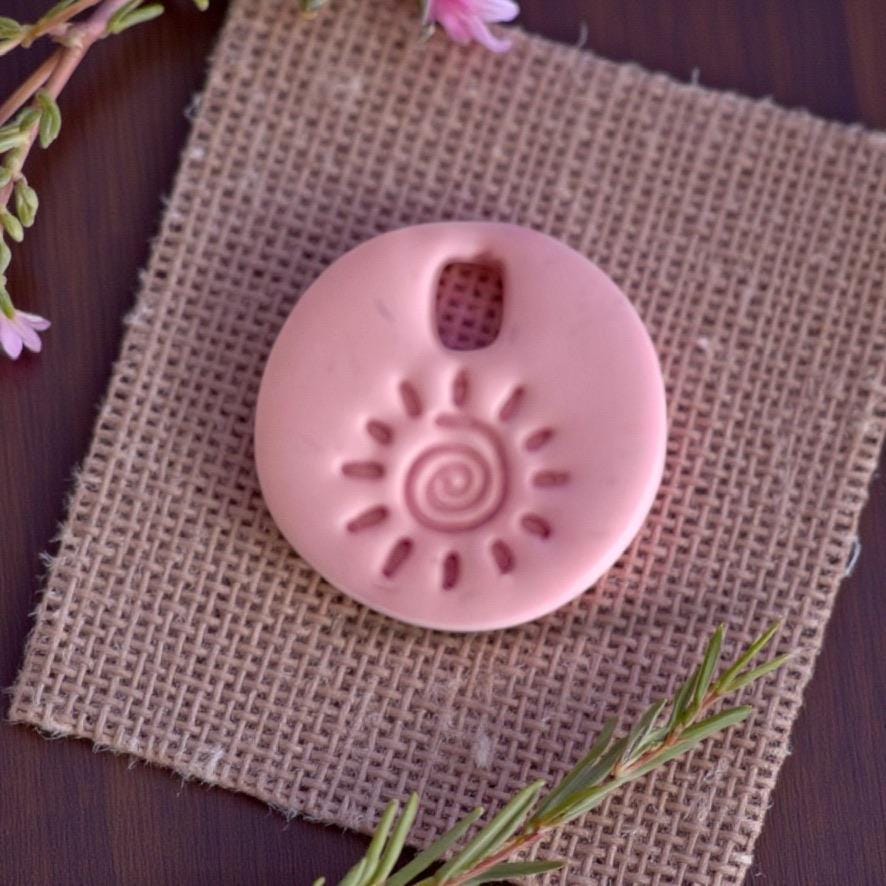 Sun swirl clay charm on burlap with greenery