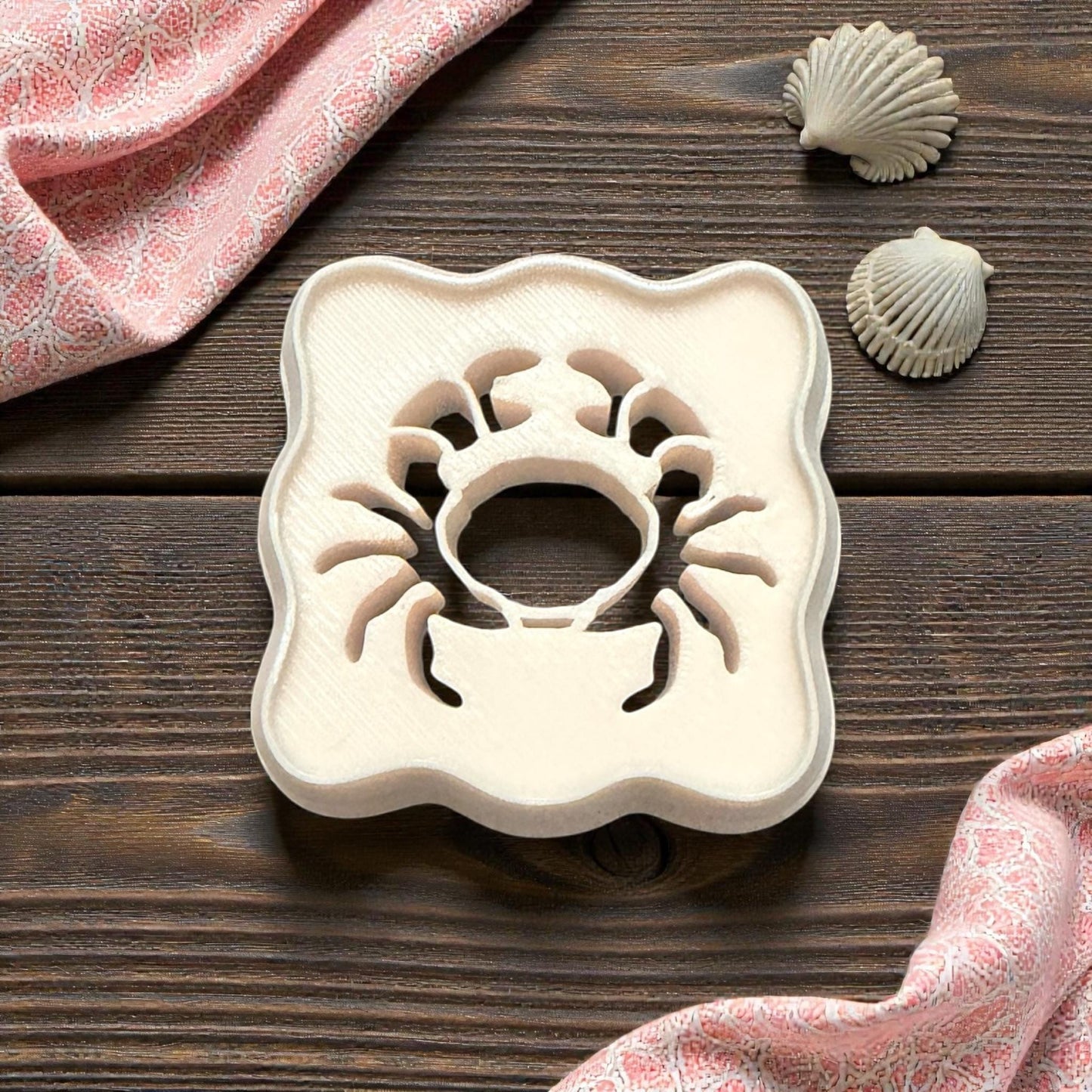 scalloped crab cutter on wooden background with shells and pink cloth
