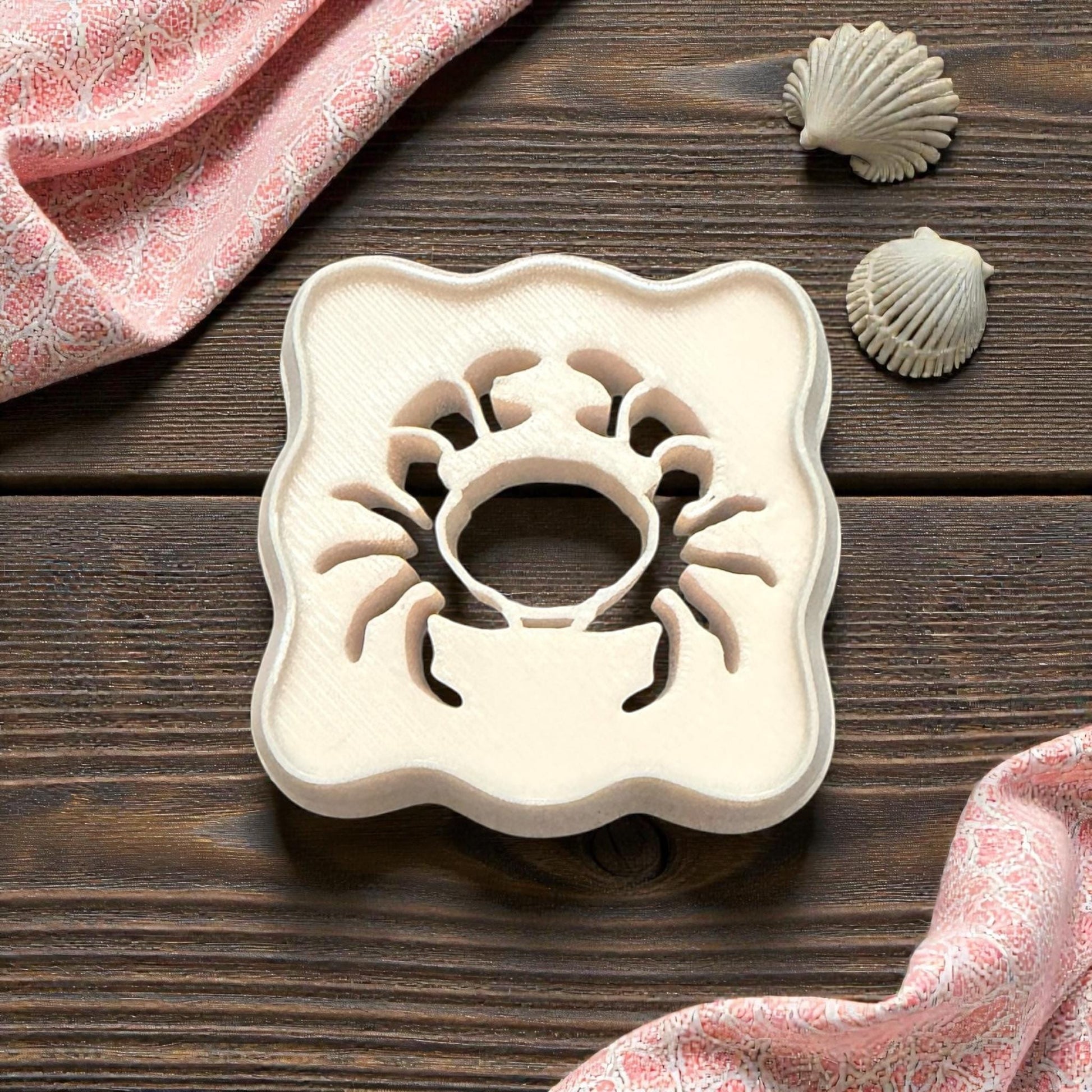 scalloped crab cutter on wooden background with shells and pink cloth
