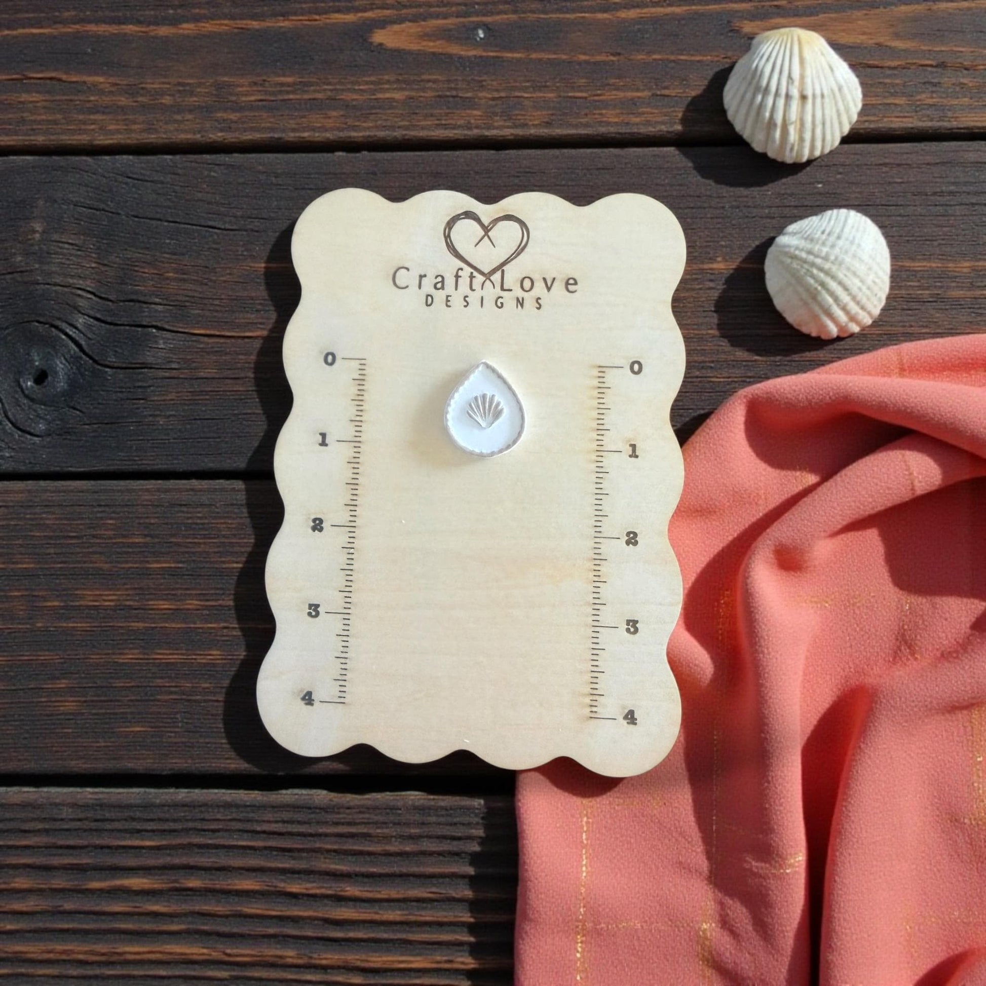small teardrop seashell imprint on wooden board with shells
