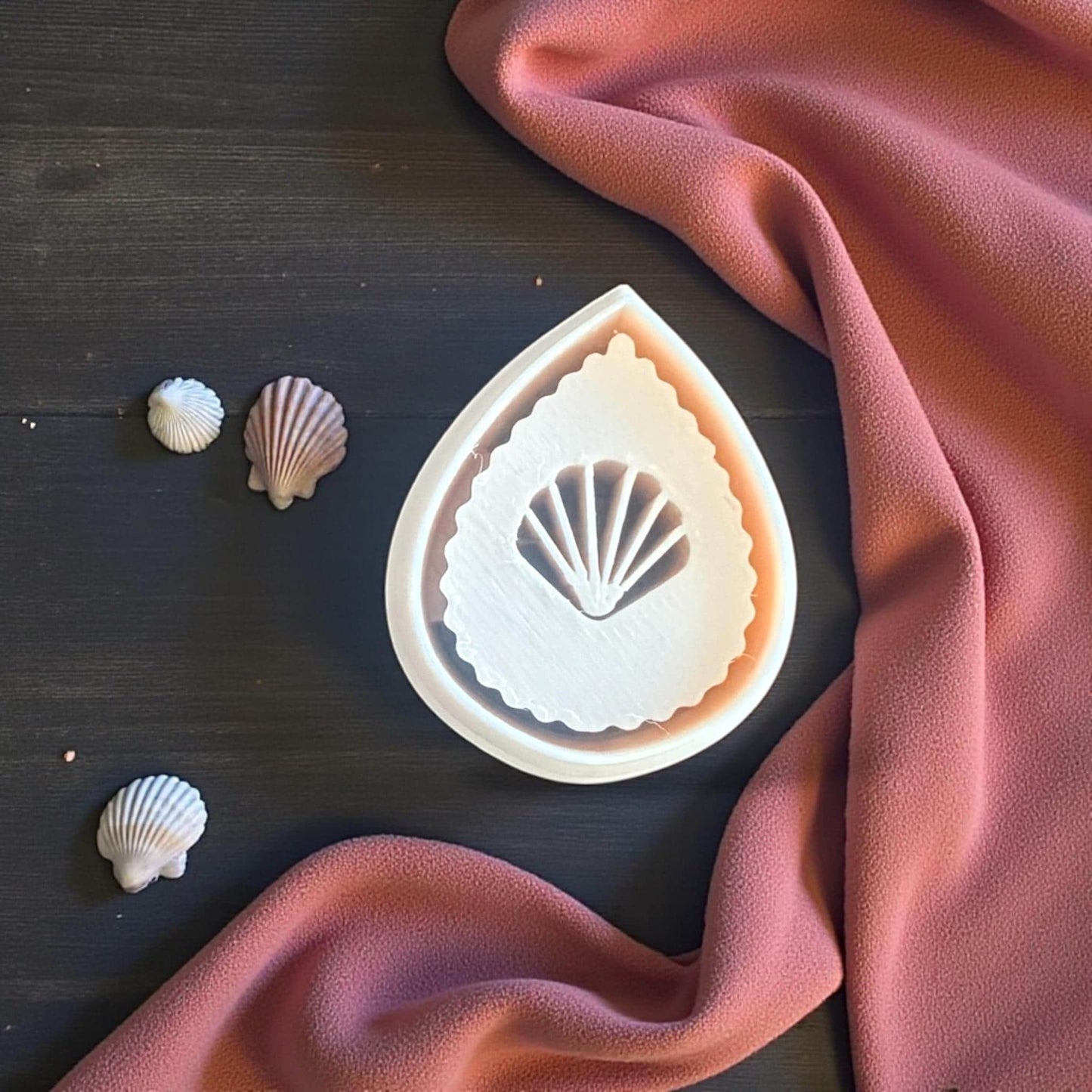 teardrop seashell cutter and imprint on wooden board with pink cloth