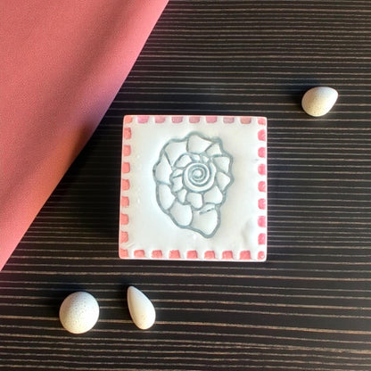 clay imprint of square shell tile design with pink scalloped border